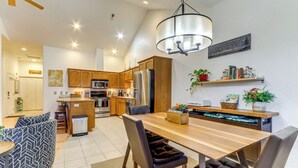 Une cuisine moderne avec des meubles en bois, un réfrigérateur en acier inoxydable et un coin repas comprenant une table en bois et des chaises en cuir.