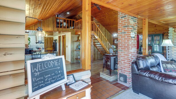 Un intérieur en bois avec un escalier, un canapé en cuir et une pancarte de bienvenue.