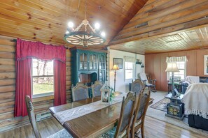 L’intérieur d’un chalet en bois comprend une table à manger, des chaises, un lustre et un coin salon chaleureux.