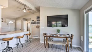 Eine moderne Küche mit weißen Schränken, einer Holz-Kochinsel mit Hockern und einem Essbereich mit Tisch und Stühlen.