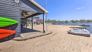 Ein Gebäude direkt am Strand mit einer überdachten Terrasse, Kajaks und einem Boot, das an der Wasserkante liegt.