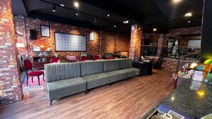 Un espacio lounge moderno con un sofá gris, sillas rojas y un muro de ladrillo.