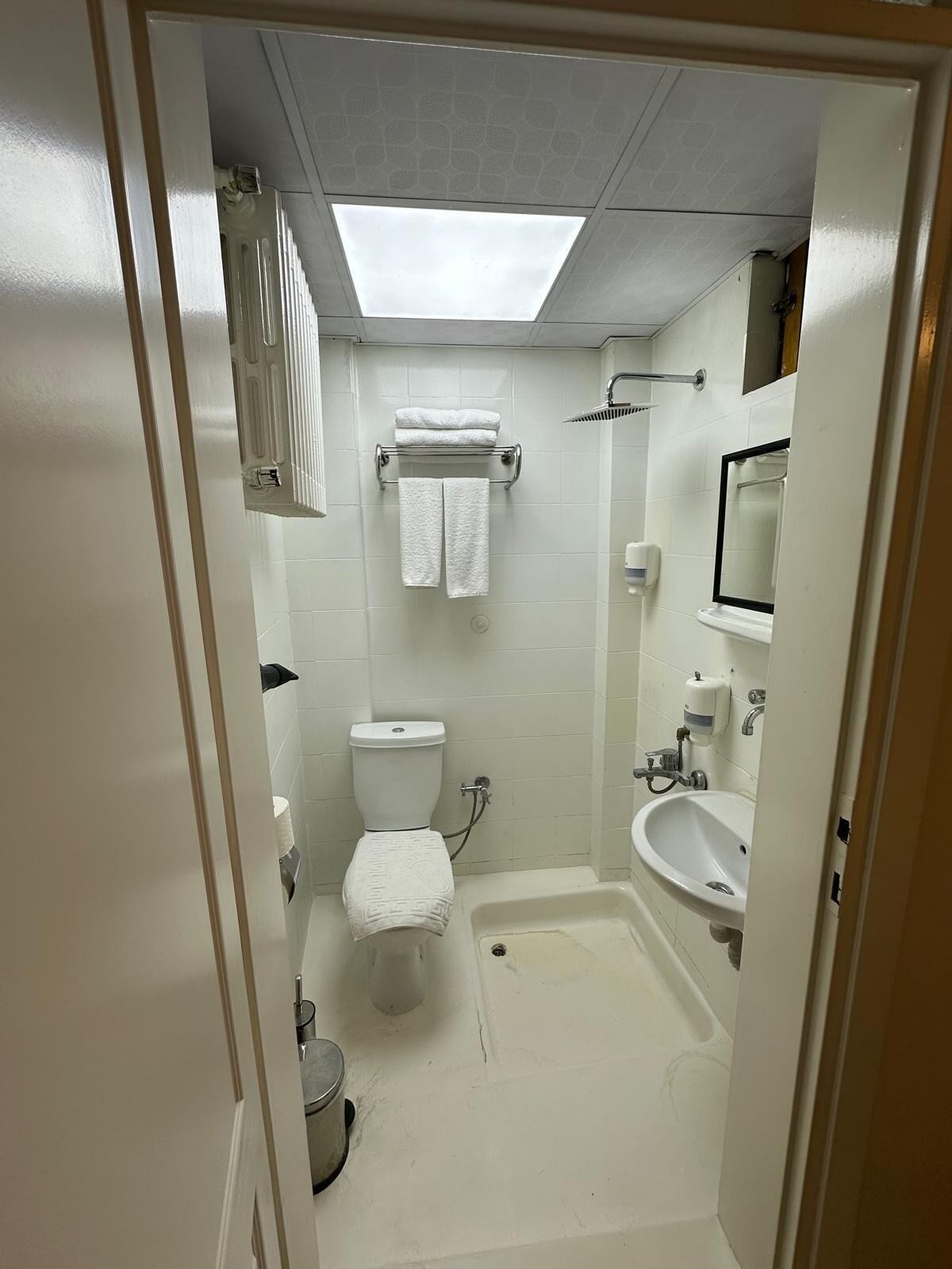 A bathroom with a toilet, sink, shower, and towel rack.