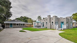 Una propiedad residencial con garaje, un patio cubierto y un edificio de piedra con puerta azul.