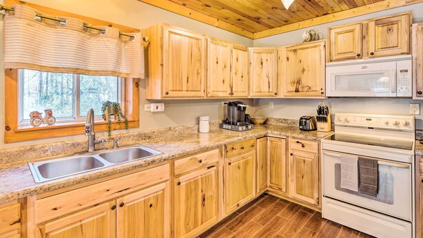 Une cuisine avec des meubles en bois, un plan de travail en granit, un évier, une cuisinière et un four à micro-ondes.