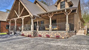 A log cabin with a covered porch, stone foundation, and a metal roof. - Riverfront Cabin w/ Hot Tub - 3 Miles to Dollywood (Pigeon Forge)