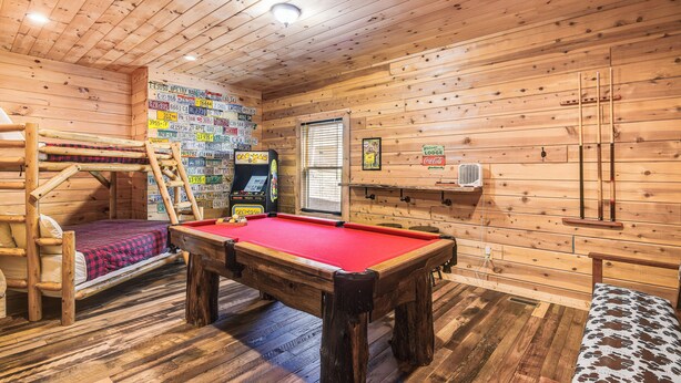 A wooden cabin with a pool table, a bunk bed, and a game machine. - Riverfront Cabin w/ Hot Tub - 3 Miles to Dollywood (Pigeon Forge)