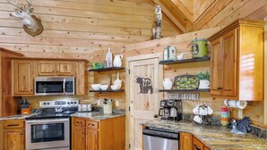 A wooden cabin-style kitchen with wooden cabinets, a built-in microwave, a stove, and a dishwasher. - Riverfront Cabin w/ Hot Tub - 3 Miles to Dollywood (Pigeon Forge)