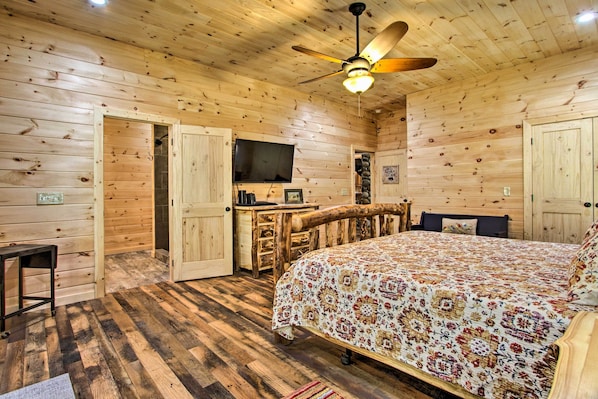 Une chambre dans une cabane en bois, avec un lit, une télévision et un bureau en bois.
