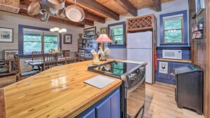 A kitchen with wooden beams, a central island, a microwave, and a refrigerator.