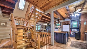 A spacious wooden interior with a central staircase, a kitchen area, and a dining space.