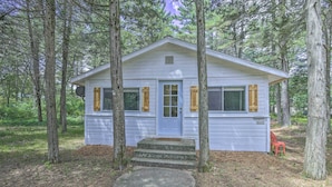 A small, single-story cabin with a front door, two windows with shutters, and a small porch area. - NEW Cute & Charming Cottage Near Castle Rock Lake! (Friendship)