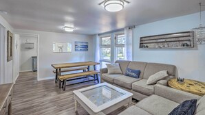 A living room with a wooden bench, a glass-top coffee table, a sofa, and a dining table. - NEW Cute & Charming Cottage Near Castle Rock Lake! (Friendship)