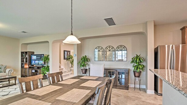 A spacious dining area with a long wooden table and chairs, a kitchen with a stainless steel refrigerator, and a living room with a television and seating. - Texas Home w/ Patio & Grill ~ 16 Mi to Austin (Manor)