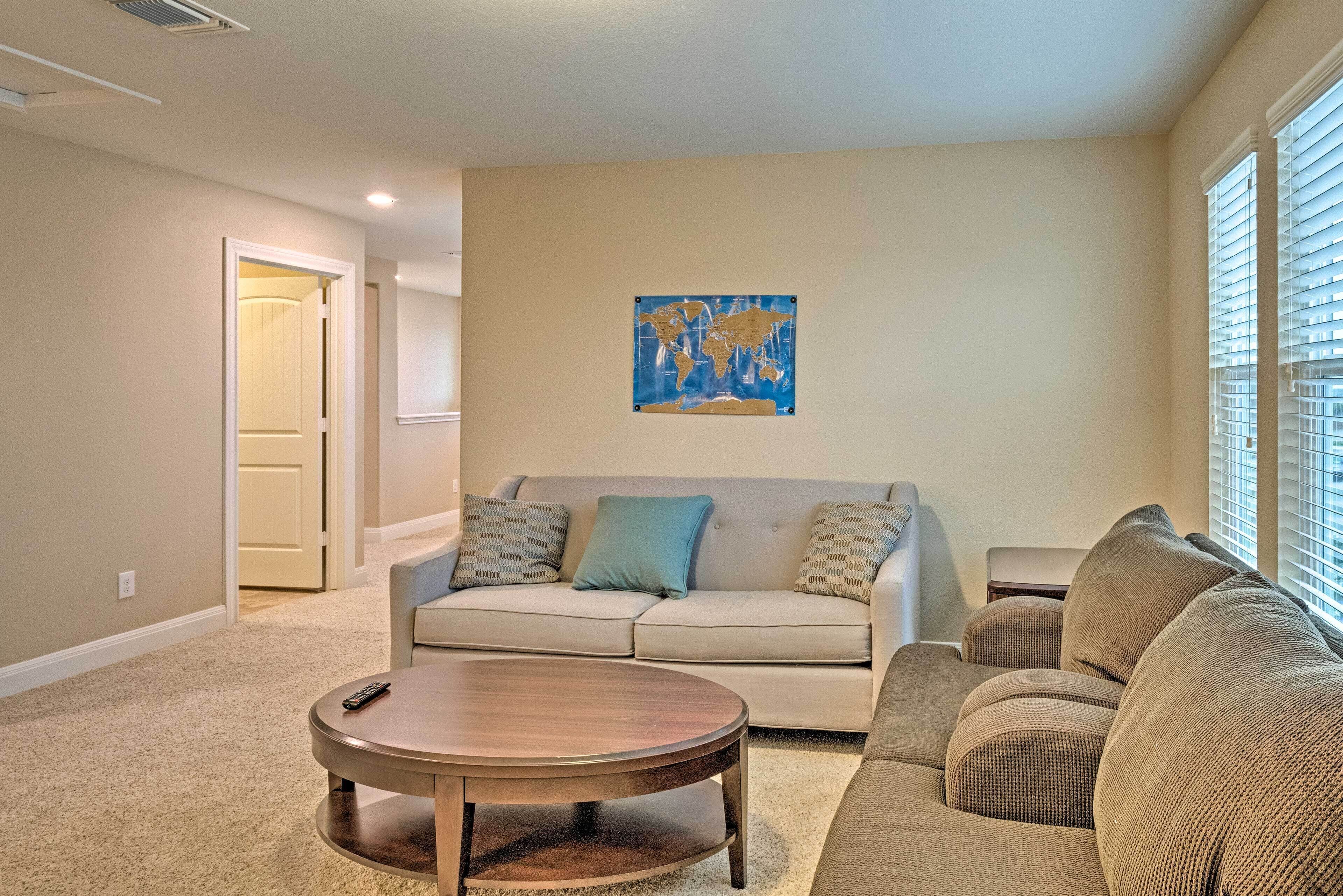 A living room with a beige sofa, a round coffee table, and a world map artwork on the wall.