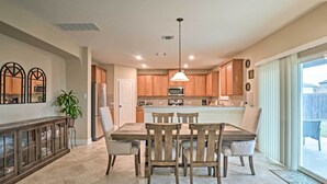 A modern kitchen with wooden cabinets, a central island, and a dining area with four chairs. - Texas Home w/ Patio & Grill ~ 16 Mi to Austin (Manor)