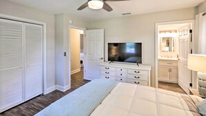Un dormitorio con cama, televisor, ventilador de techo, cómoda y vestidor.