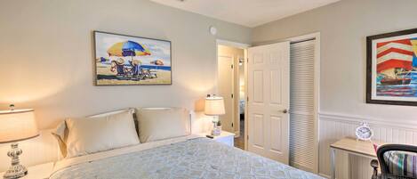 A bedroom with a bed, nightstands, a ceiling fan, a door, and a painting on the wall.