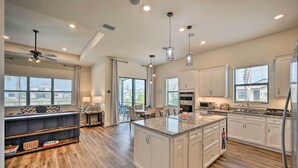 A spacious kitchen with a large island, white cabinetry, and a dining area with a table and chairs. - Luxury Ave Maria Rental w/ Private Pool & Spa! (Immokalee)