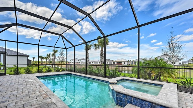 A swimming pool with a brick deck and a glass enclosure. - Luxury Ave Maria Rental w/ Private Pool & Spa! (Immokalee)