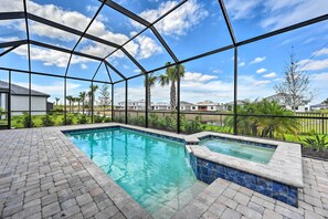 Una piscina con plataforma de ladrillo y cerramiento de cristal.