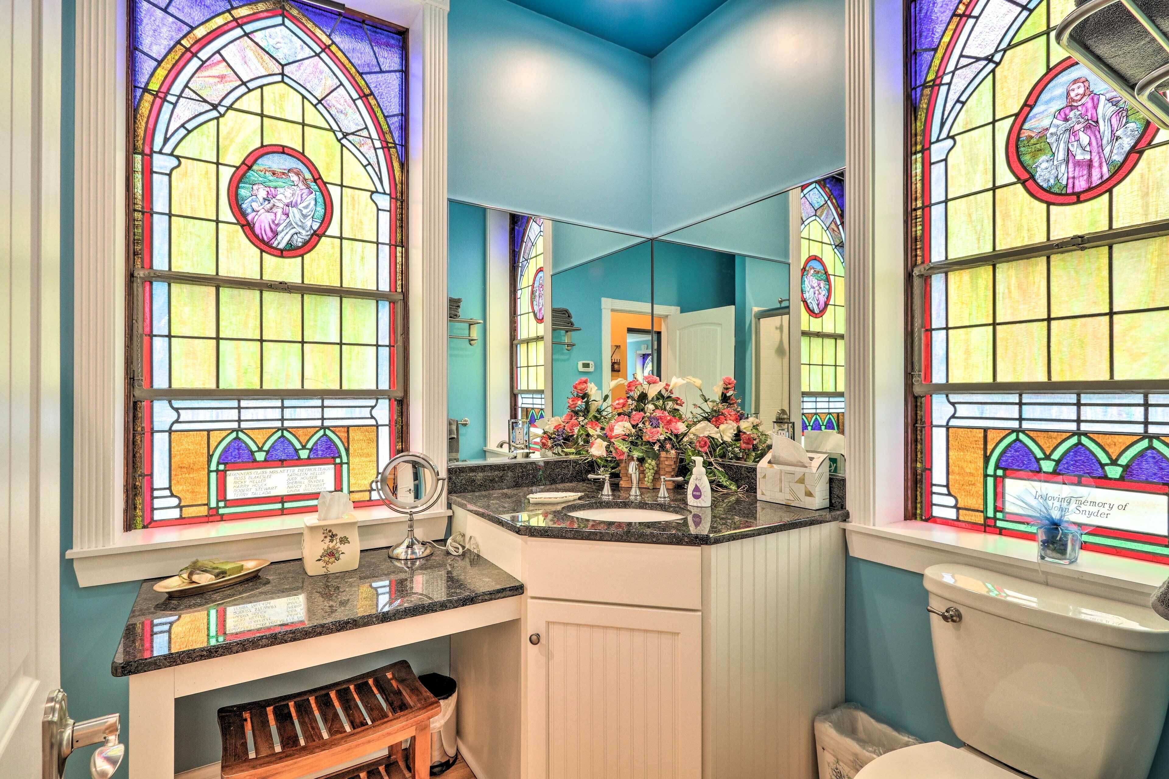 A bathroom with stained glass windows, a sink, and a toilet.