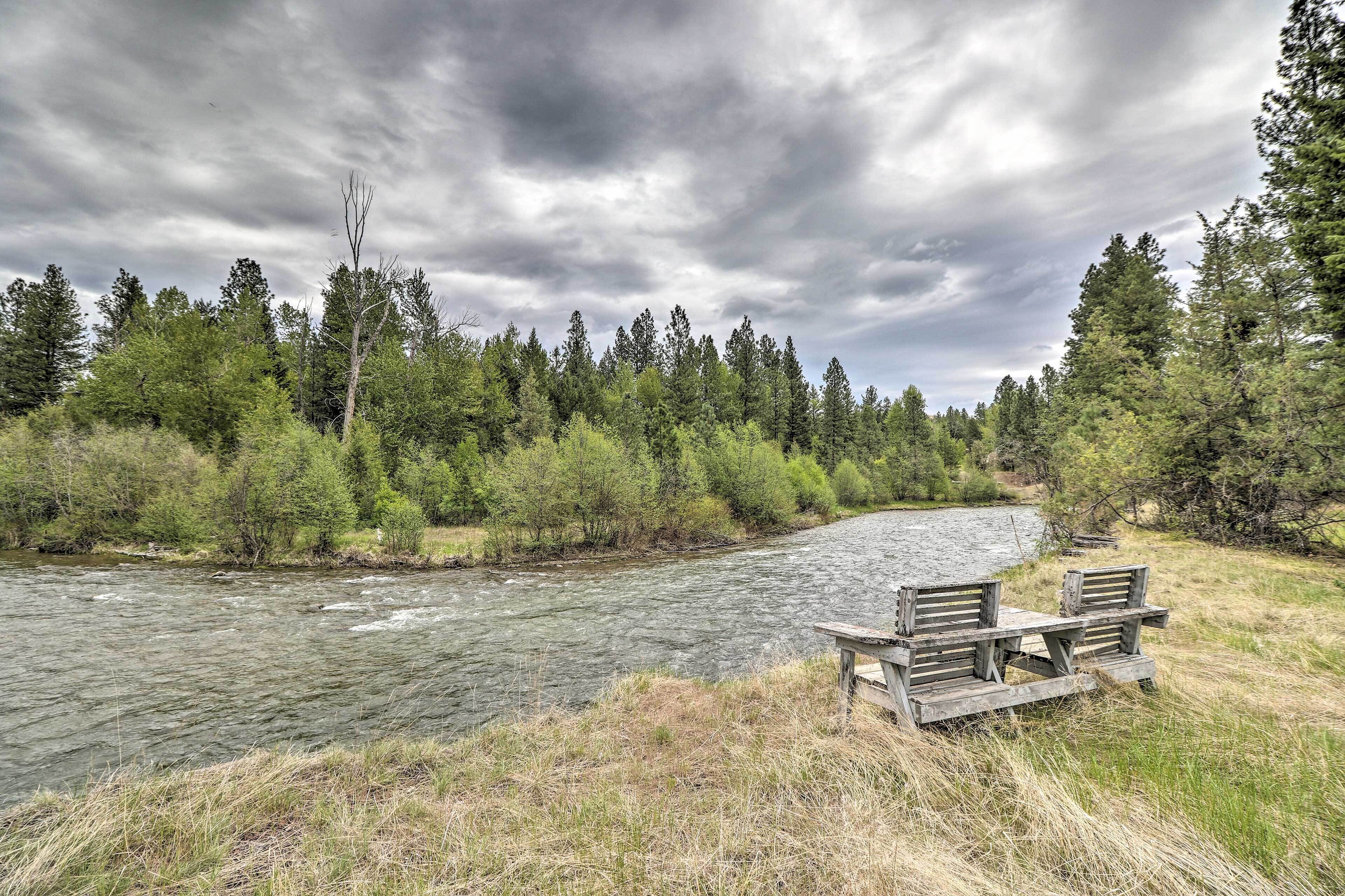 A river with a wooden bench and picnic table on the bank.
