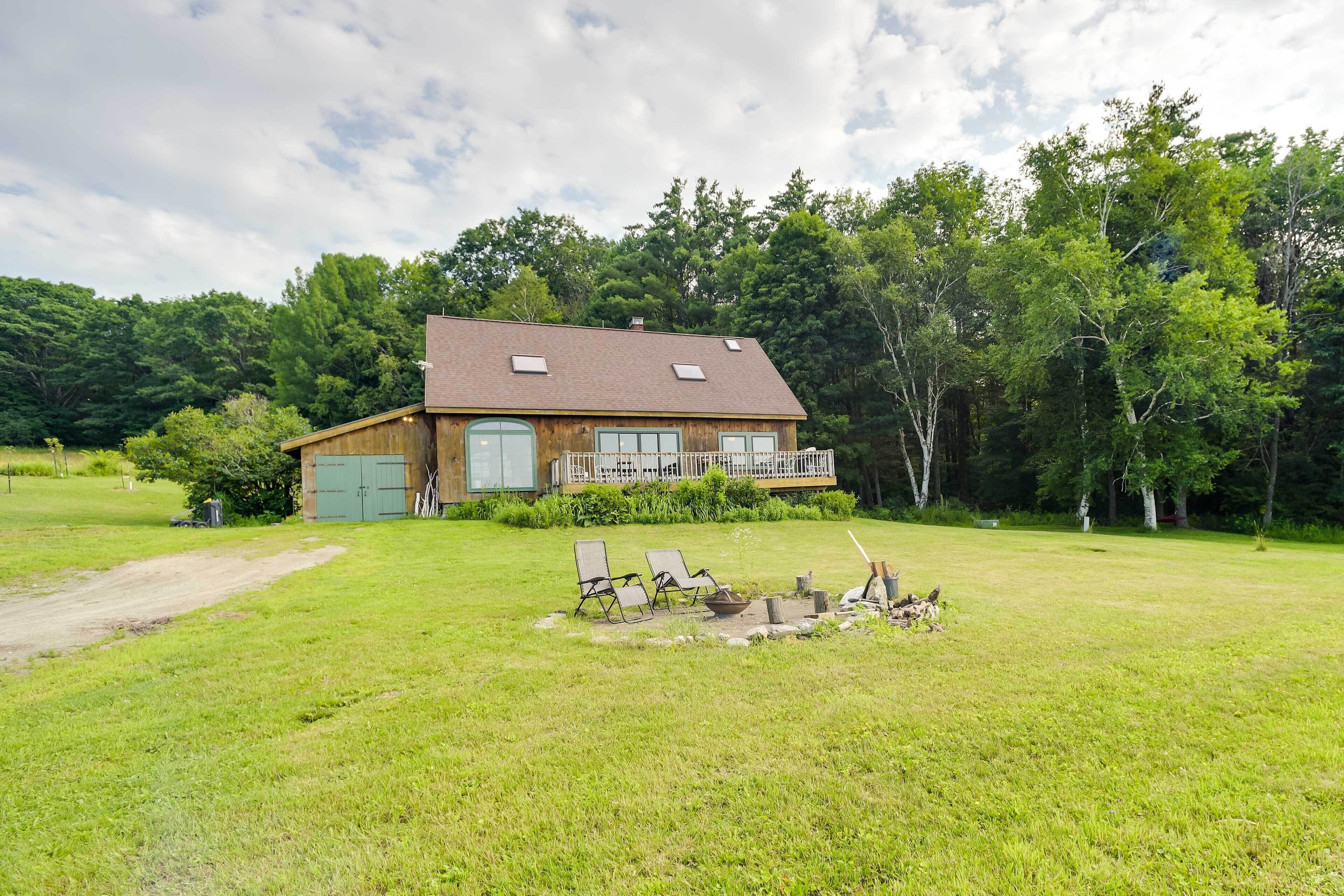 A wooden house with a porch, a lawn, and a dirt path leading to the house.