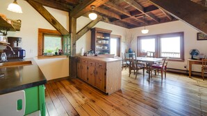 A kitchen with wooden beams, a countertop, and a dining area with chairs and a table. - Breathtaking Mtn Views: Stylish Rustic Retreat! (Bennington)