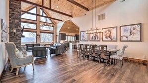 A spacious living area with a high ceiling, wooden beams, a stone fireplace, and a dining area with a large table and chairs. - Mountainside Family Retreat w/ Deck in Banner Elk! (Banner Elk)