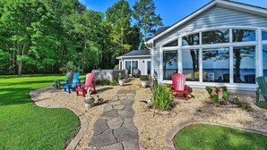 A house with a stone pathway leading to a patio area with Adirondack chairs. - Bayfront Blounts Creek Home: Private Beach + Dock! (Blounts Creek)