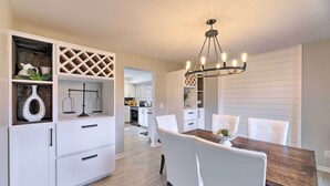 A modern kitchen with white cabinetry, a wooden dining table, and a chandelier. - Luxury Maineville Villa w/ Private Pool & Deck (Maineville)