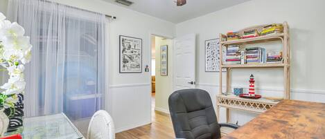 A dining area with a wooden table, chairs, a bookshelf, and a ceiling fan.