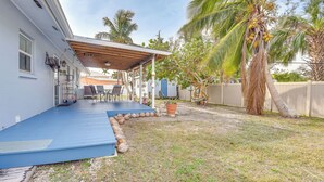 Un patio techado con piso azul, una pérgola de madera y un pequeño espacio de estar con mesa y sillas.