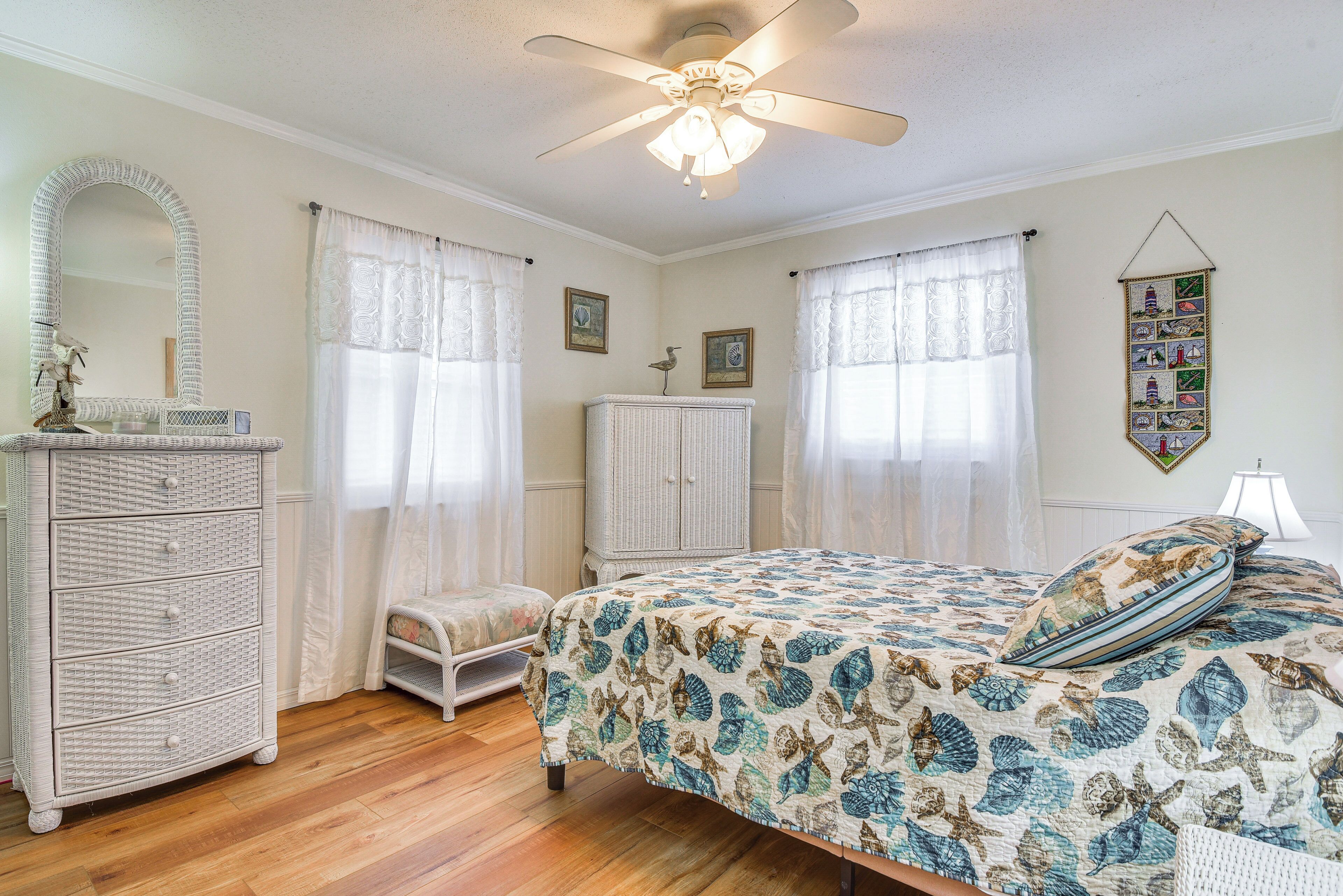 A bedroom with a bed, dresser, and a ceiling fan.