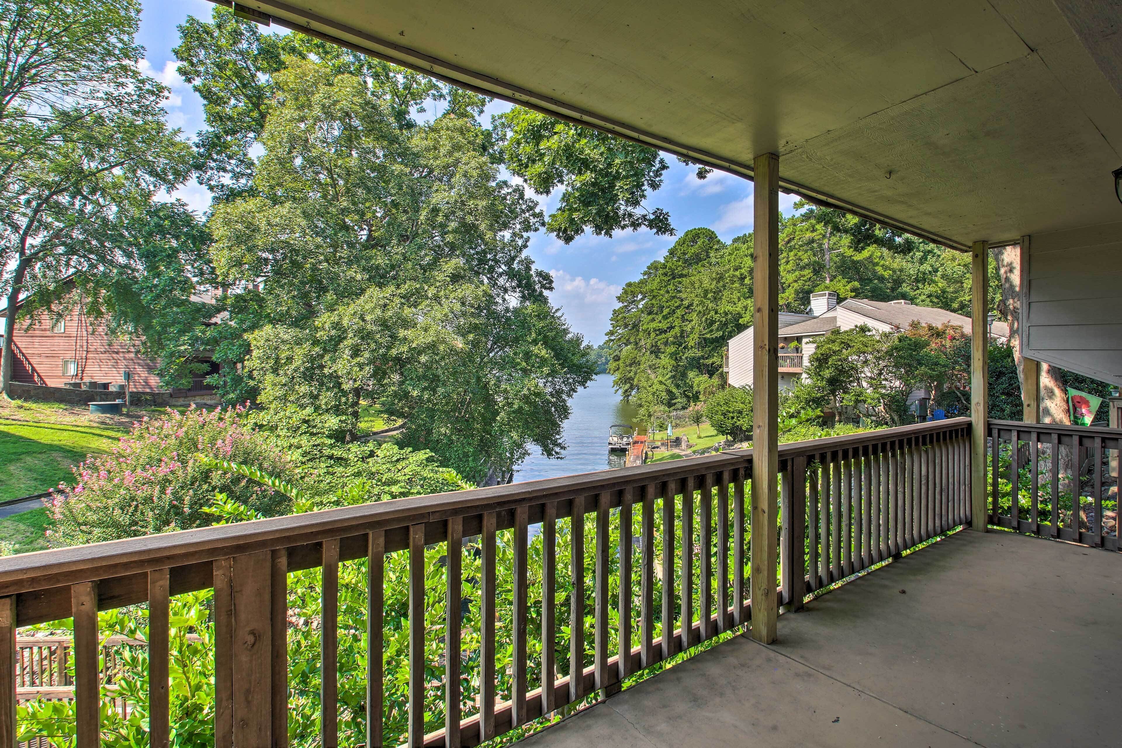 A covered porch with a view of a river and surrounding greenery.