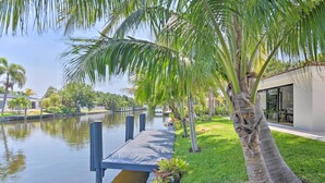 A wooden dock extending into a calm body of water, surrounded by lush greenery and palm trees. - Luxe Wilton Manors Home w/ Private Boat Dock (Wilton Manors)