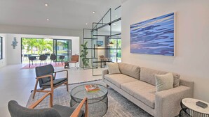 A modern living room with a sofa, chairs, a coffee table, and a large window. - Luxe Wilton Manors Home w/ Private Boat Dock (Wilton Manors)