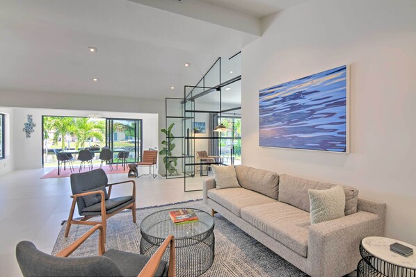 A modern living room with a sofa, chairs, a coffee table, and a large window offering a view of the outdoors.