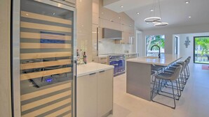 A modern kitchen with a large island, bar stools, and a view of the outdoors. - Luxe Wilton Manors Home w/ Private Boat Dock (Wilton Manors)