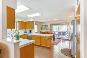 A modern kitchen with wooden cabinets, a central island, and a view to a dining area.