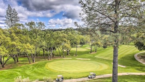 Ein Golfplatz mit einem gepflegten Grün, Sandbunkern und blauem Himmel.