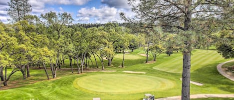 Ein Golfplatz mit einem gepflegten Grün, Sandbunkern und blauem Himmel.