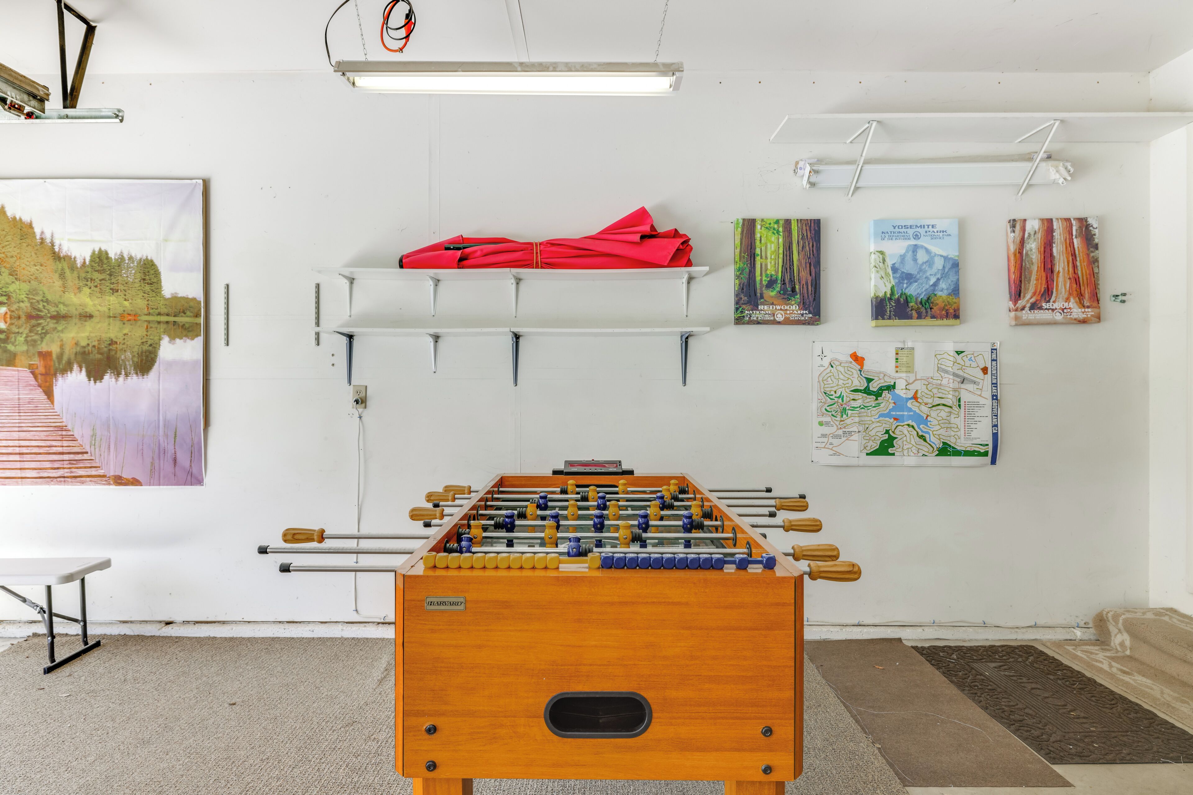 A room with a foosball table, a red umbrella, and a map on the wall.