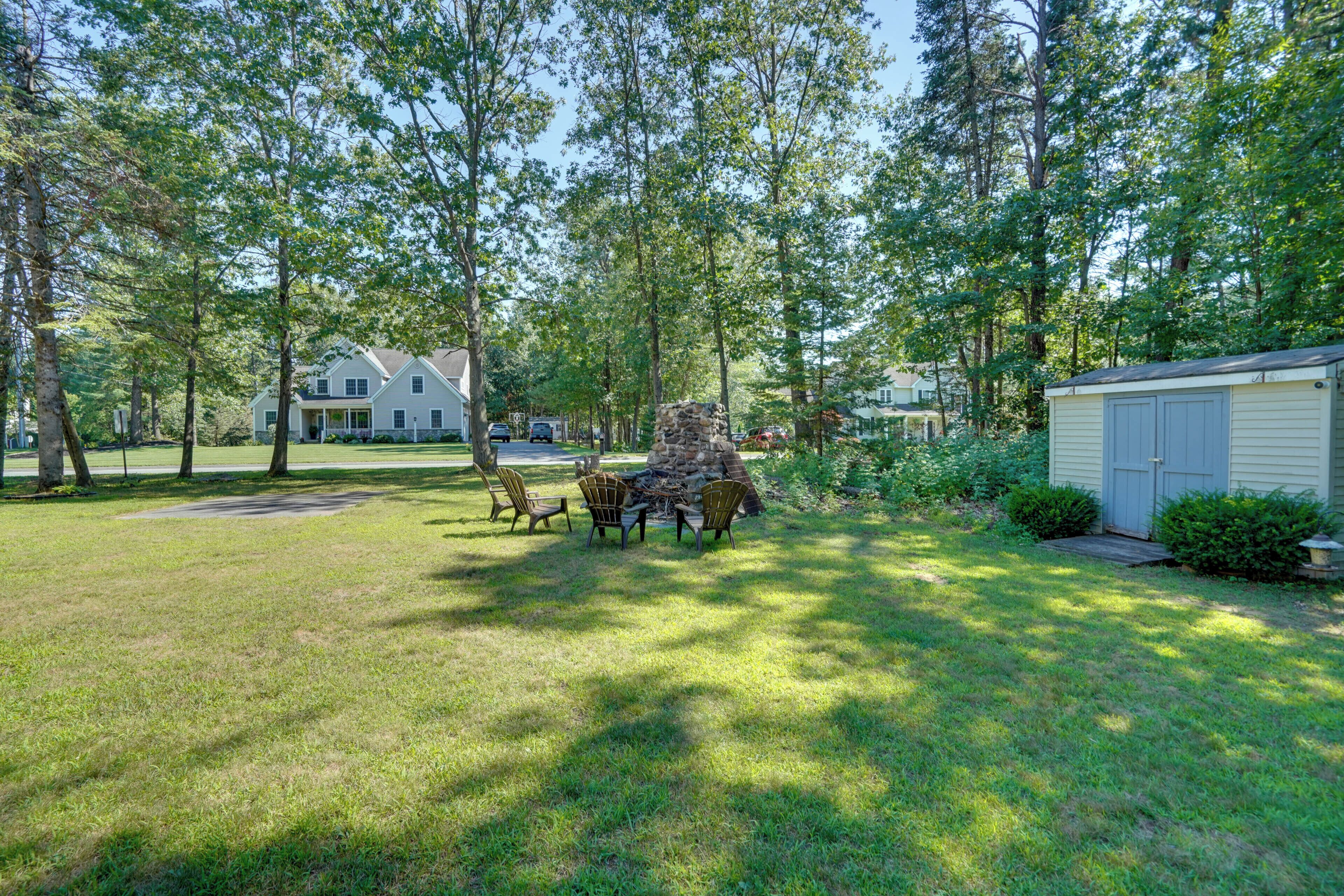 A residential area with a stone fireplace, outdoor seating, and a small shed.