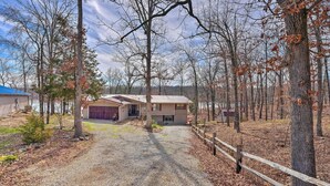 A gravel driveway leading to a house with a garage, surrounded by trees and a wooden fence. - Lakefront Vacation Rental w/ Deck & 2 Docks! (Williford)