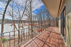 A wooden deck with a metal railing overlooking a body of water and trees. - Lakefront Vacation Rental w/ Deck & 2 Docks! (Williford)