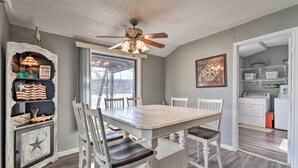 A dining area with a wooden table and chairs, a ceiling fan, and a window with a view. - Lakefront Vacation Rental w/ Deck & 2 Docks! (Williford)