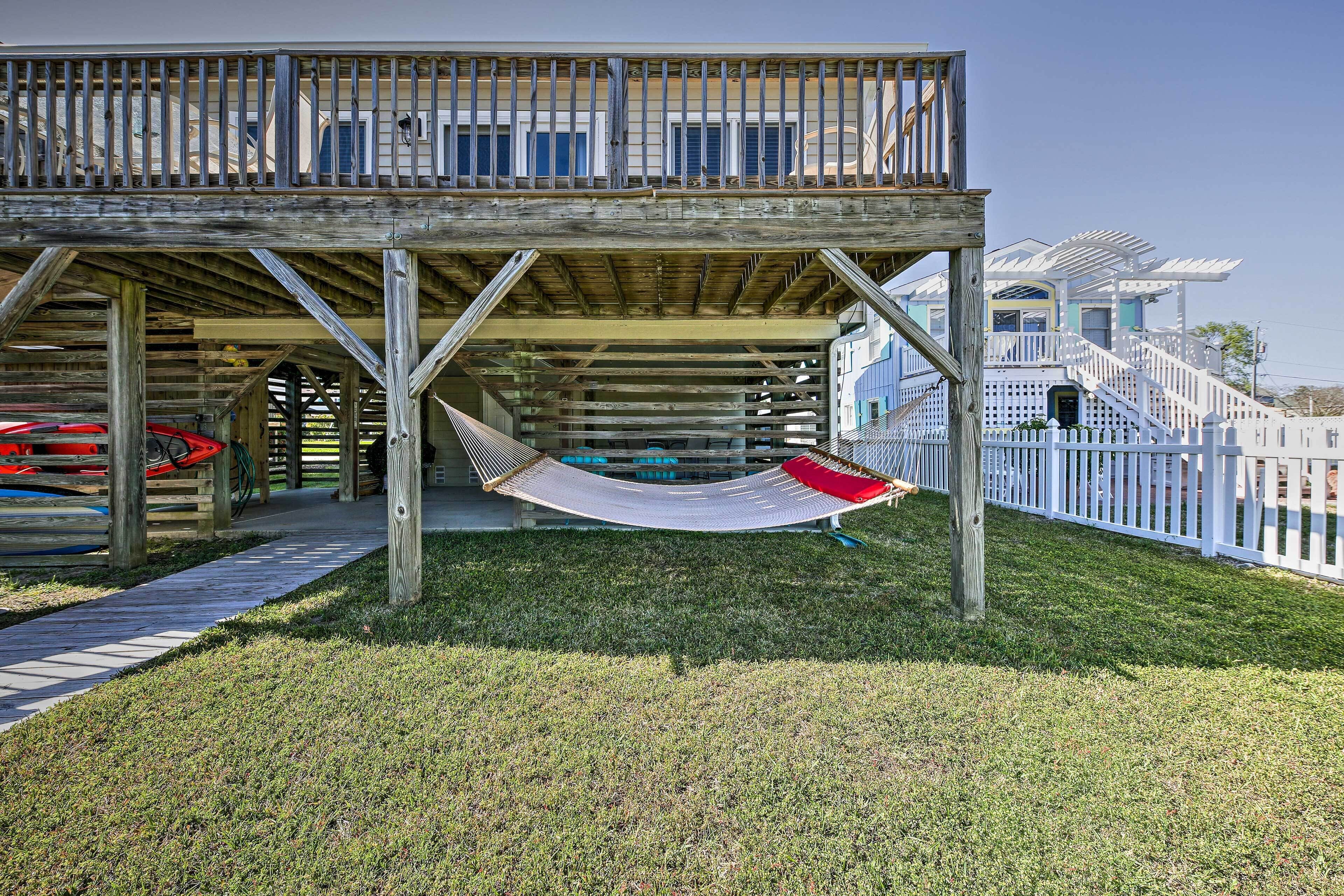 A wooden deck with a hammock, a pathway, and a white fence.