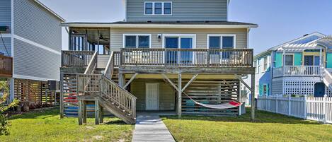 A two-story house with a wooden deck and a covered front porch.